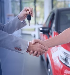 Consultor entregando a chave de um carro novo ao cliente